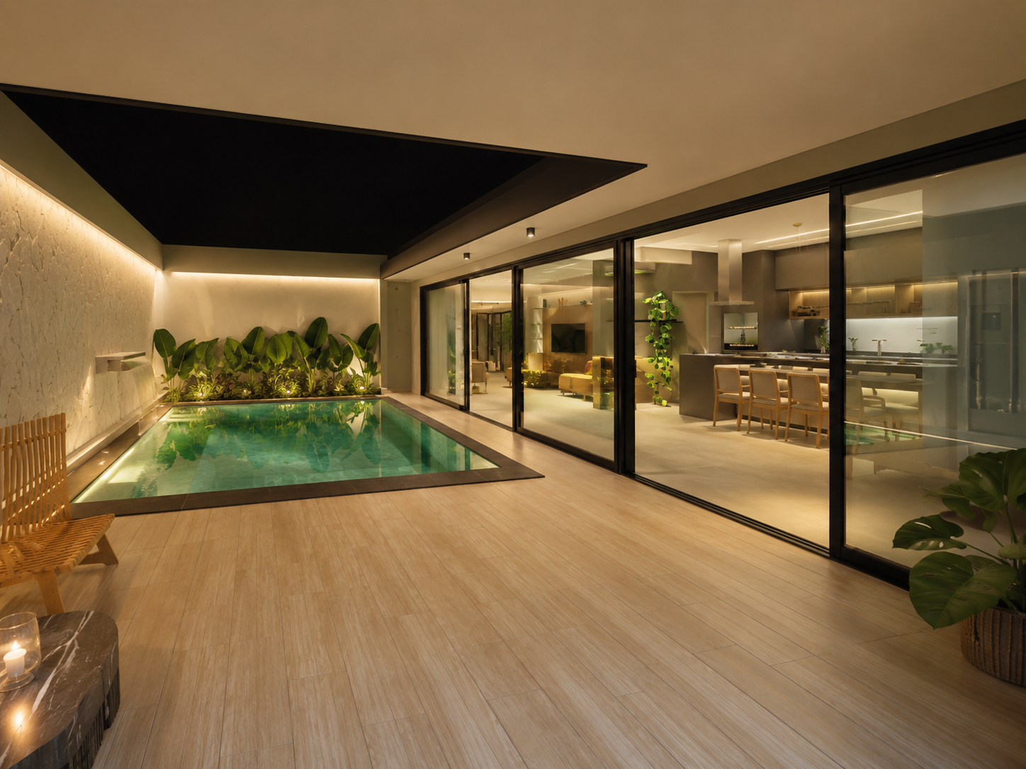 Pátio interno com piscina, deck em madeira, jardim vertical de folhagens tropicais e integração visual com sala e cozinha através de portas de vidro.